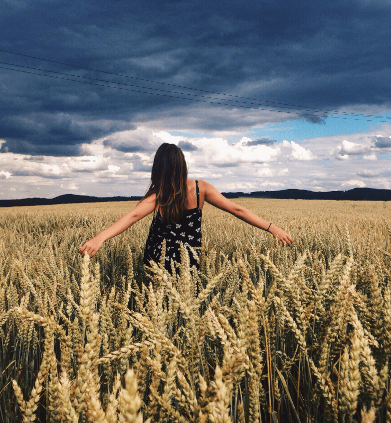 Woman with arms out stretched in a field of wheat